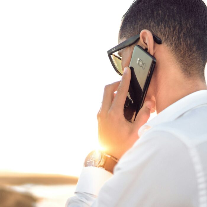 man holding smartphone standing in front of calm body of water