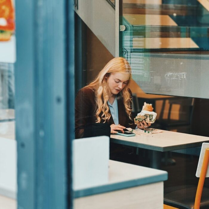 Woman eating a sandwich at a cafe table.