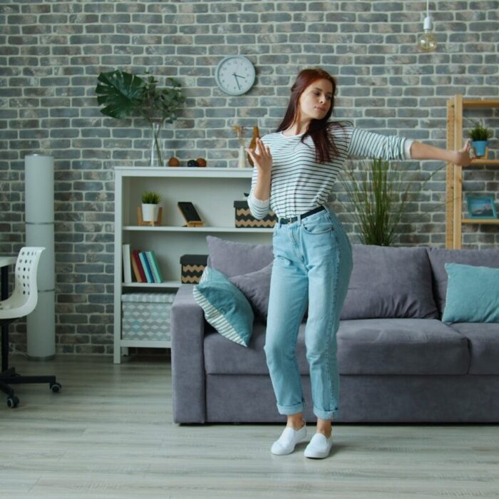 Young woman dancing happily in a modern living room.
