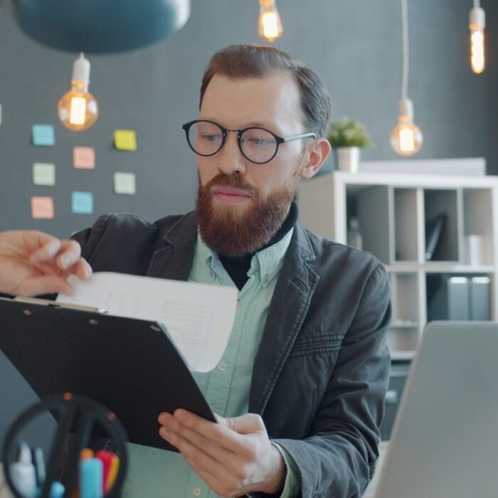 Man in glasses reviewing documents at desk